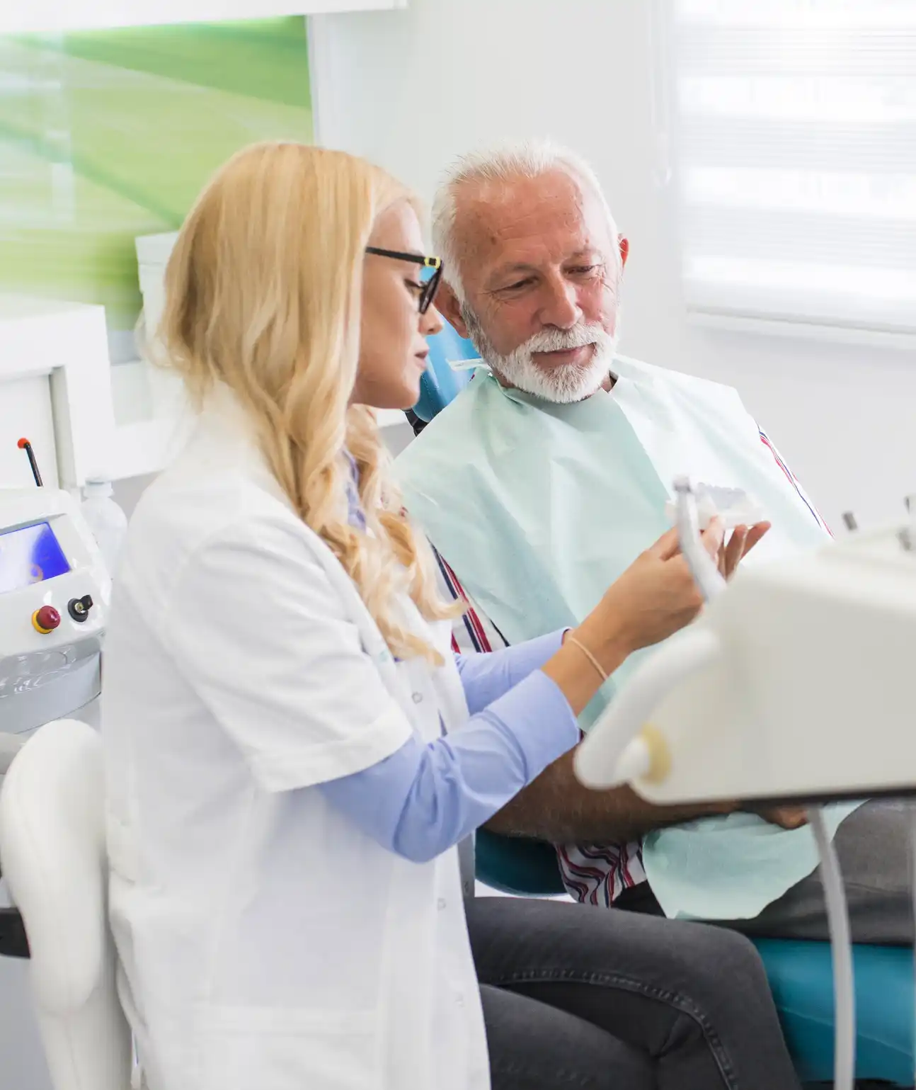 A man sits in a chair while a doctor attendant explains a machine