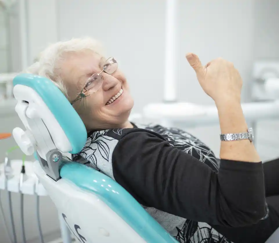 A woman gives a thumbs up while in a dental chair