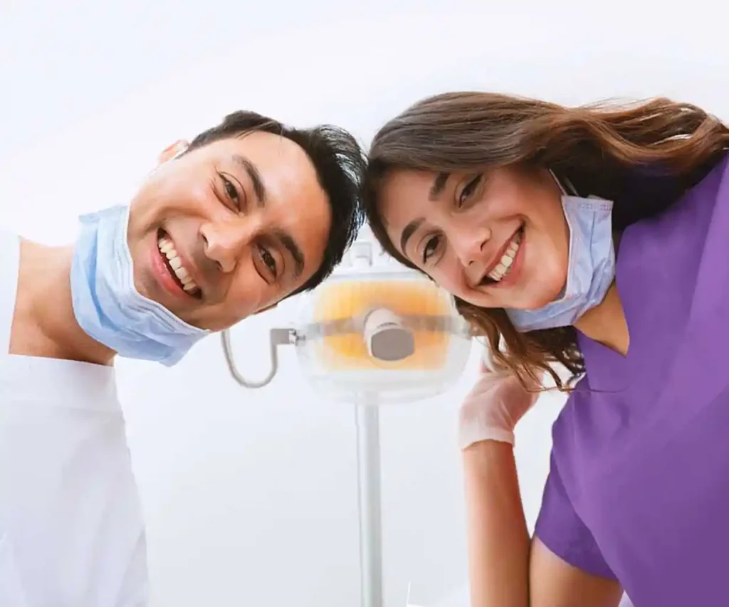 Two dentist look down over a patient as they smile